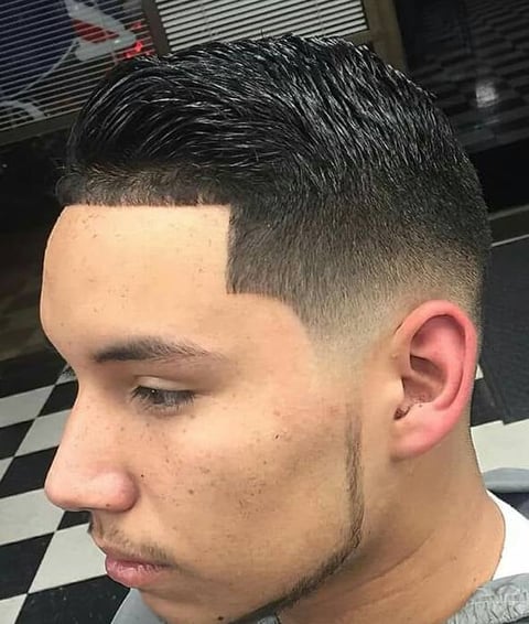Man with fade haircut and beard shown in profile view against checkered barber shop background