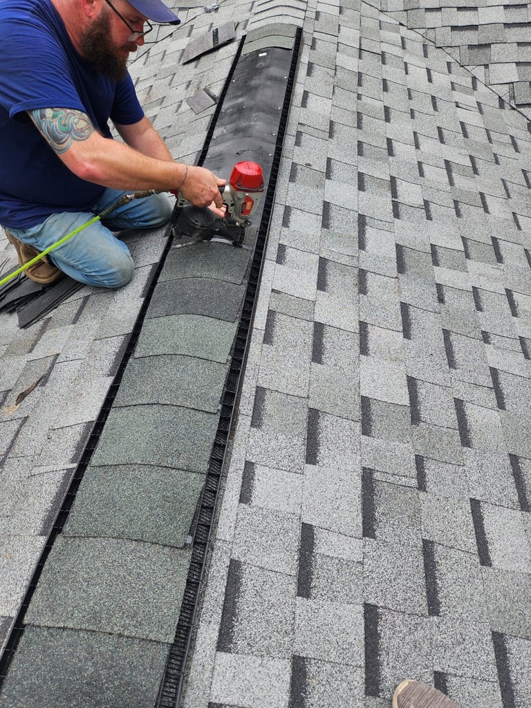 Roofer installing asphalt shingles on roof edge with power tools near gutter system