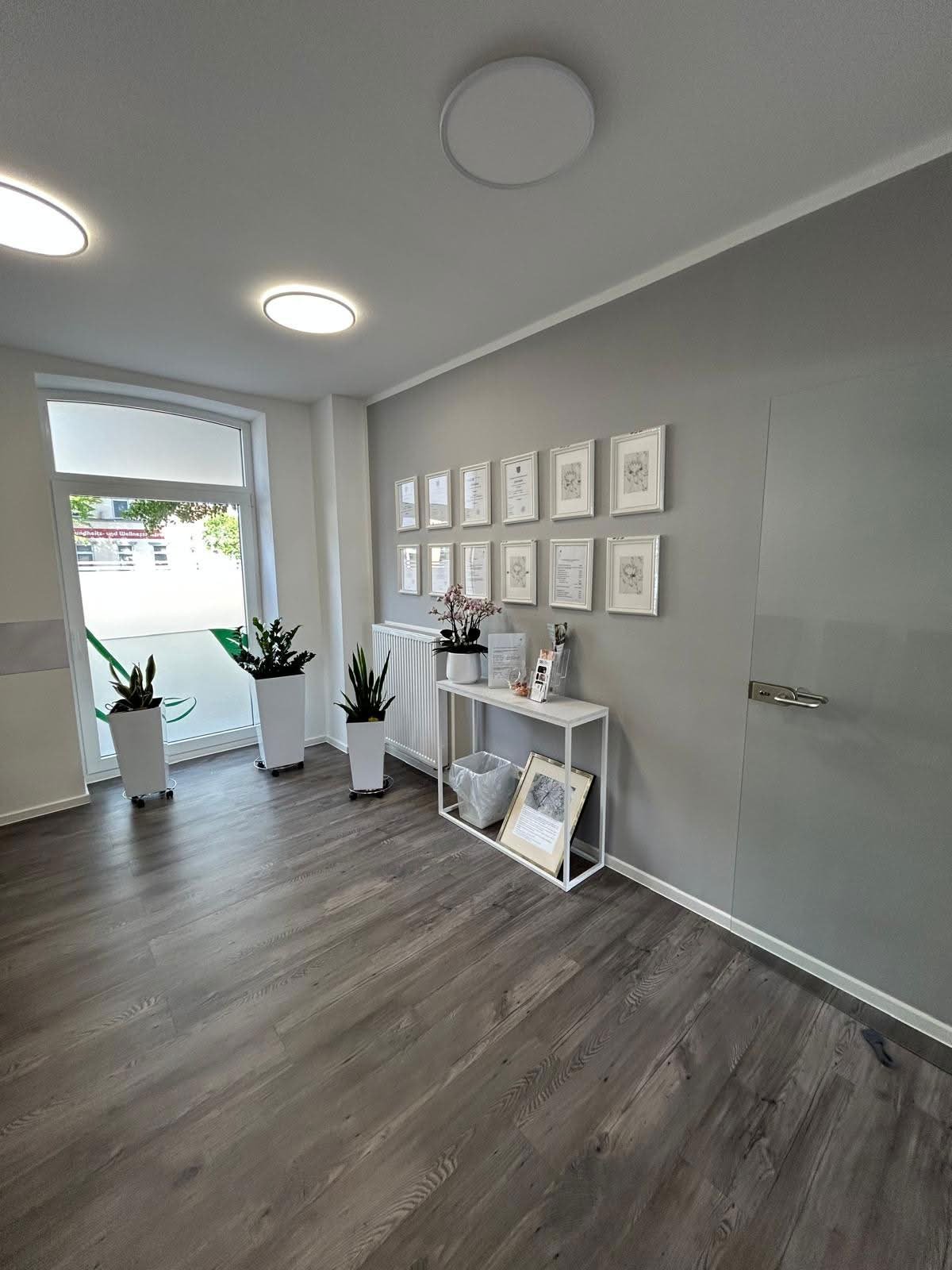 Wartezimmer mit gerahmten Urkunden an der Wand und Sideboard mit Pflanzen