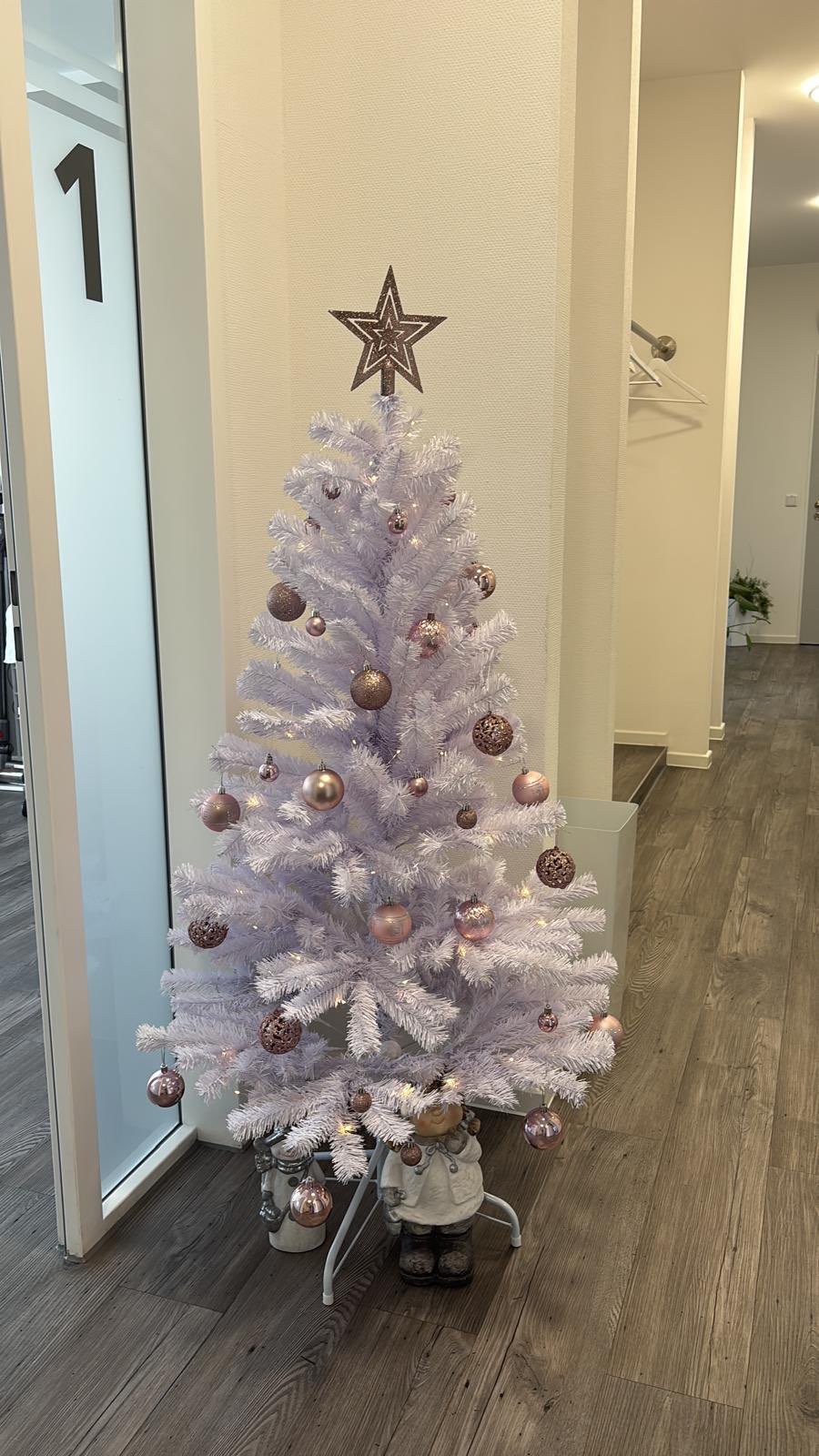 Weißer Weihnachtsbaum mit rose-goldenen und bronze-farbenen Kugeln und schwarzem Stern in der Praxis