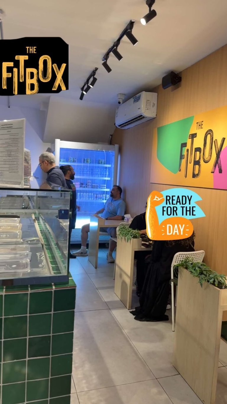 Interior of The Fitbox gym with customers at counter, colorful branding on walls, and Ready for the Day sign visible
