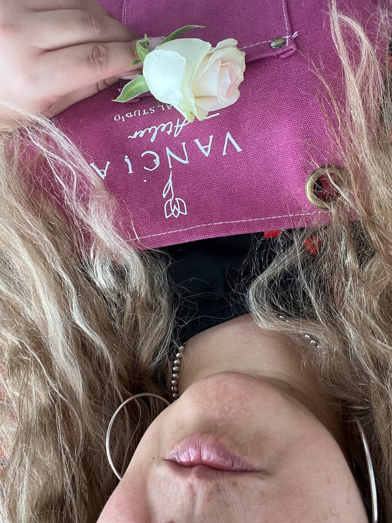 Person holding a pink book with a cream-colored rose corsage, long wavy hair visible, overhead view