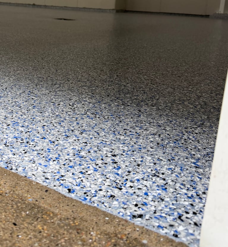 Close-up of a polished concrete floor with blue and white speckled epoxy coating and light-colored concrete base visible at the edge