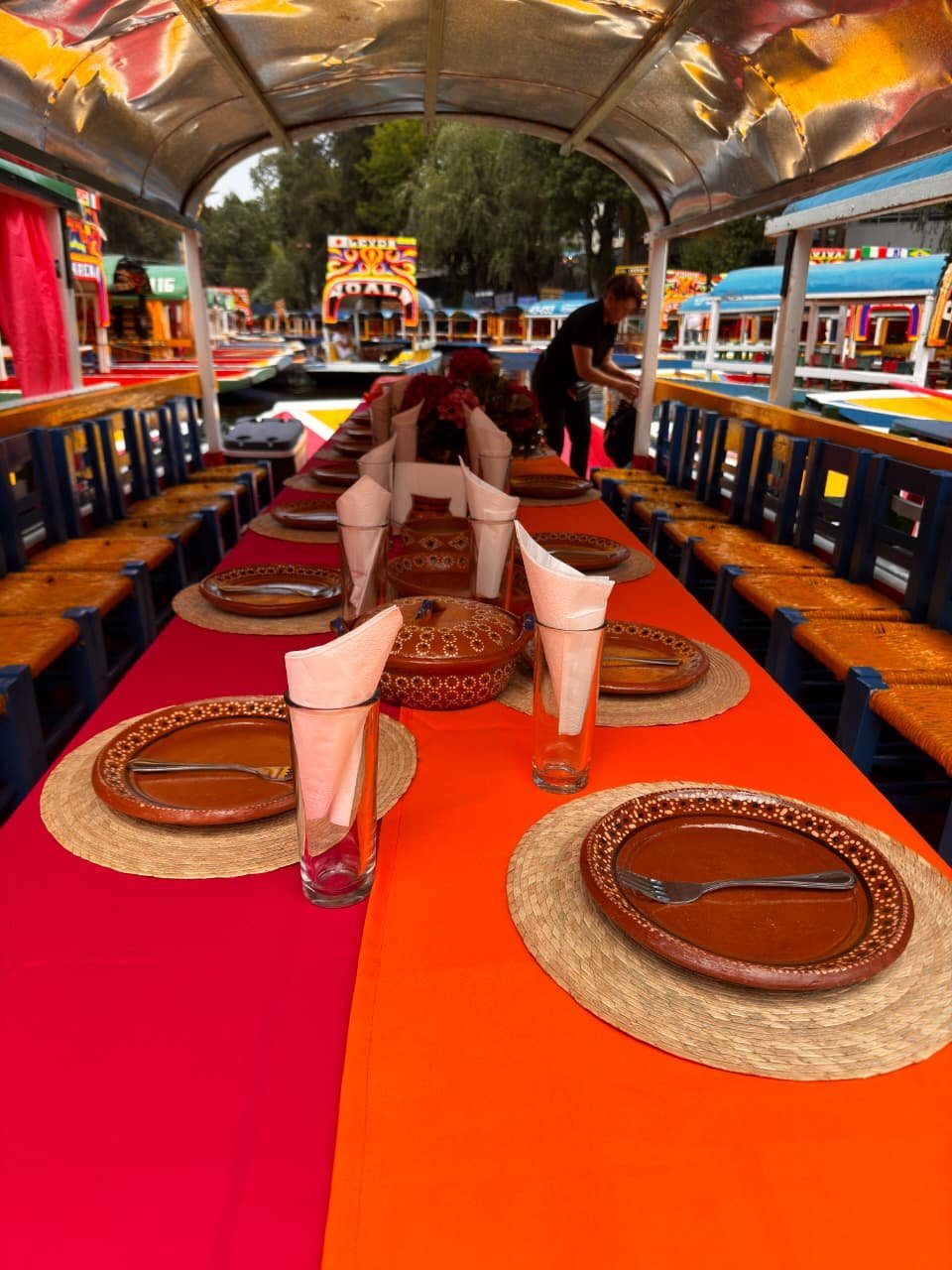 Mesa servida estilo mexicano con mantel colorido y platos de barro sobre una trajinera en Xochimilco