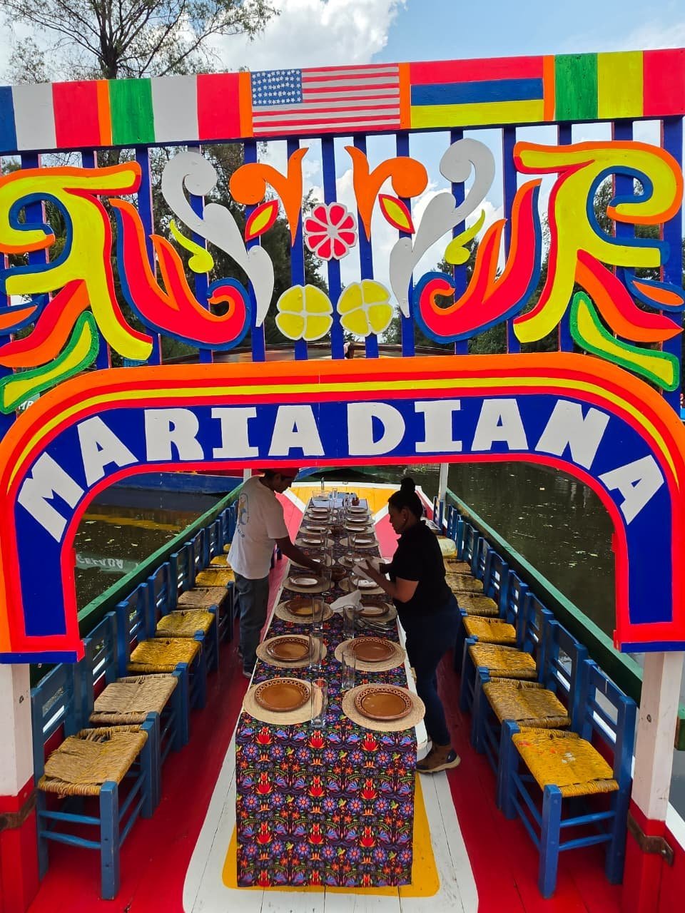 Interior de trajinera decorada con manteles mexicanos, listo para una celebración gastronómica