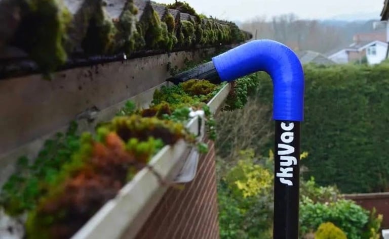 Blue and black rain gutter downspout with Angloc branding installed on residential garden fence