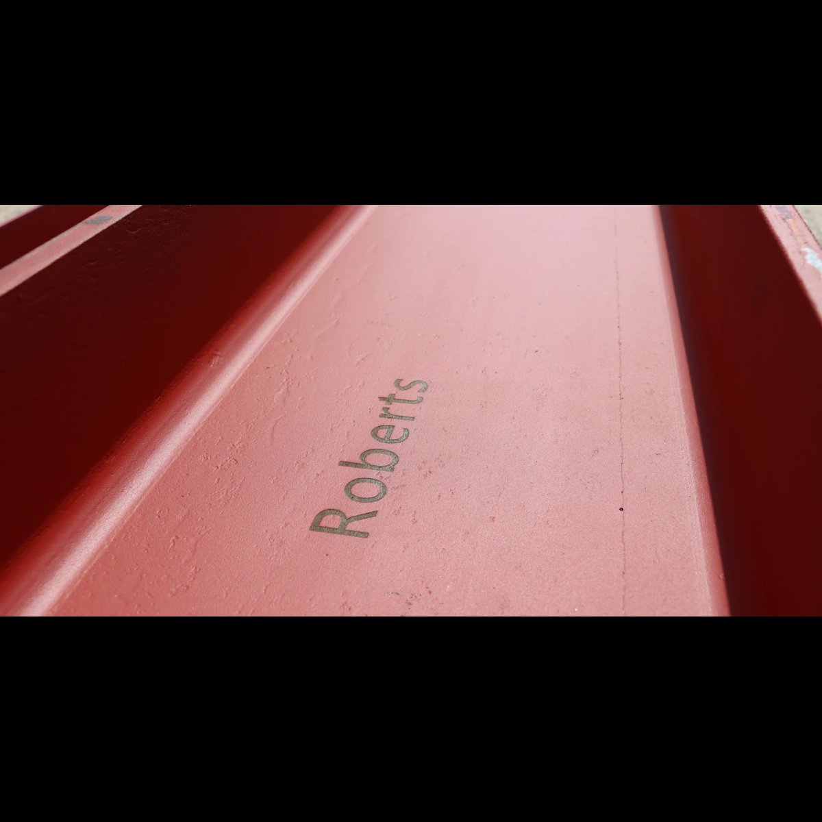 Close-up of Roberts name engraved on a pink surface between dark red borders