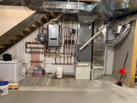 Unfinished basement with HVAC system, copper plumbing, water heater, and construction materials
