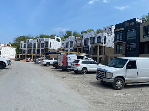 Construction site with multi-story residential buildings under development, parked work vehicles, and building materials visible