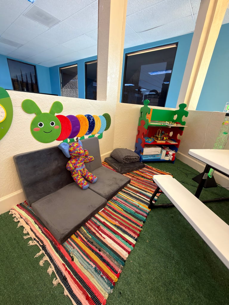 Colorful childrens reading nook with gray cushioned seat, caterpillar wall mural, striped rug, and educational toys in a bright blue room