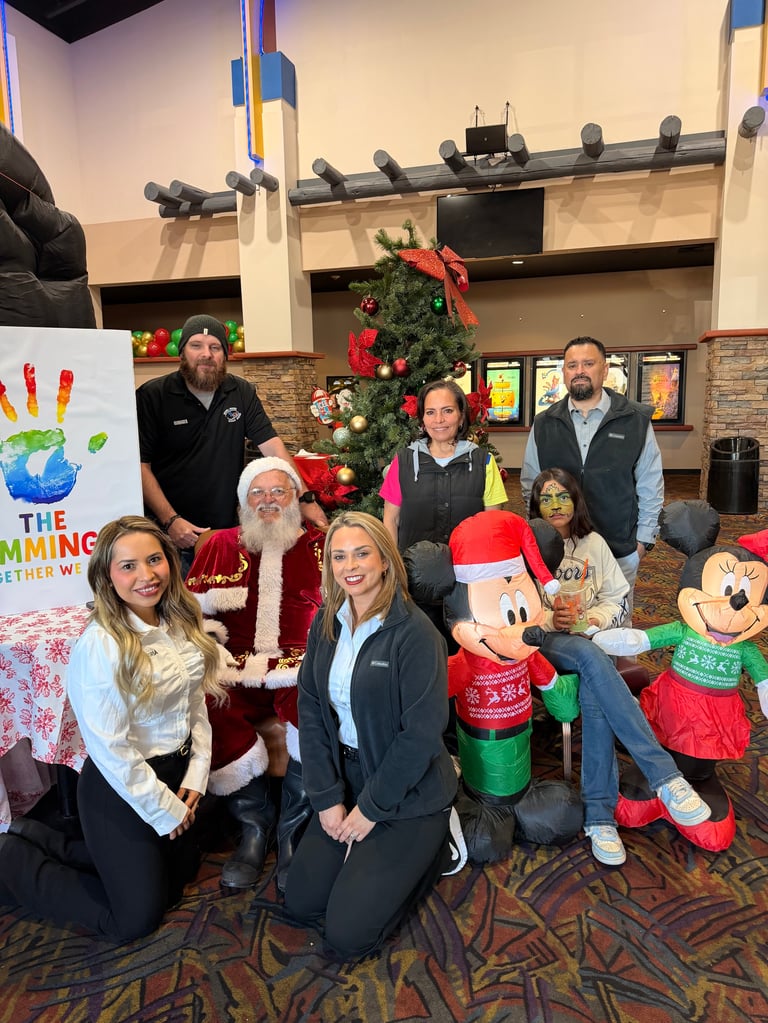Group of people posing with Santa and Christmas decorations inside a community center during a holiday event