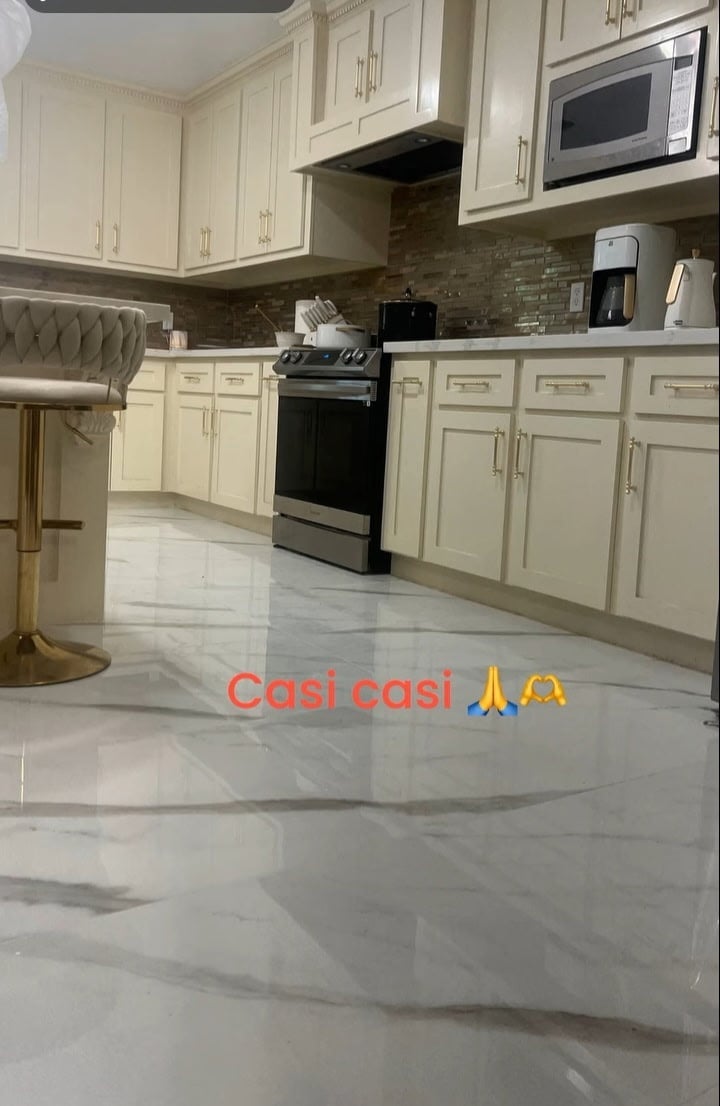 Modern kitchen with cream cabinets, black stove, stainless steel microwave, and polished marble flooring
