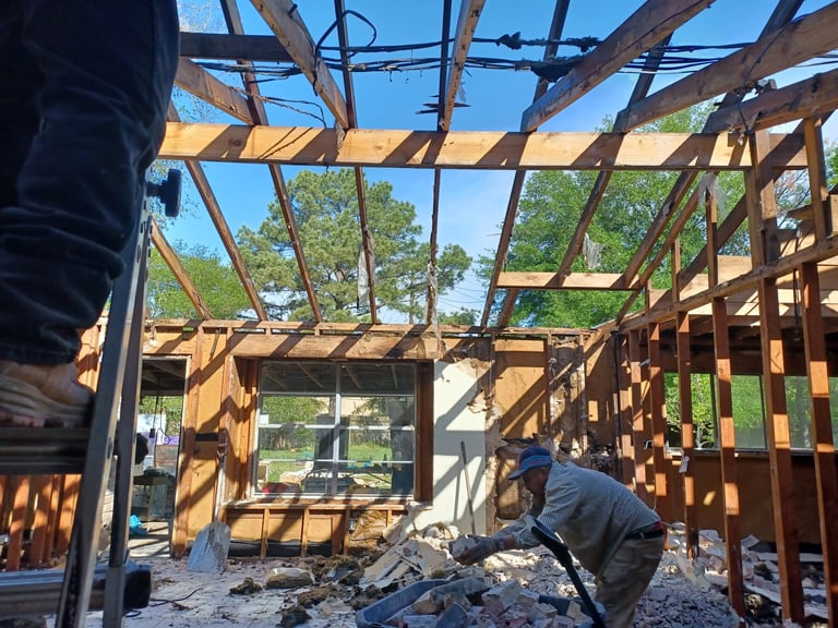 Construction worker building wooden framed house structure with exposed beams and window openings — apartment framing