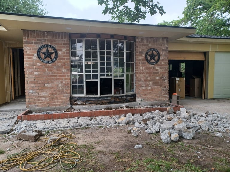 Brick storefront building undergoing renovation with exposed foundation work, decorative stars, and landscaping stones in front