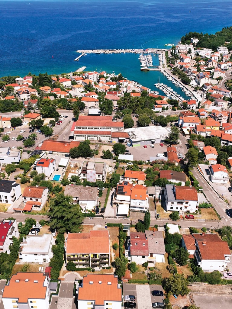 Zračni pogled na Malinsku — mediteranski gradić s terakota krovovima, marinom i tirkiznim morem