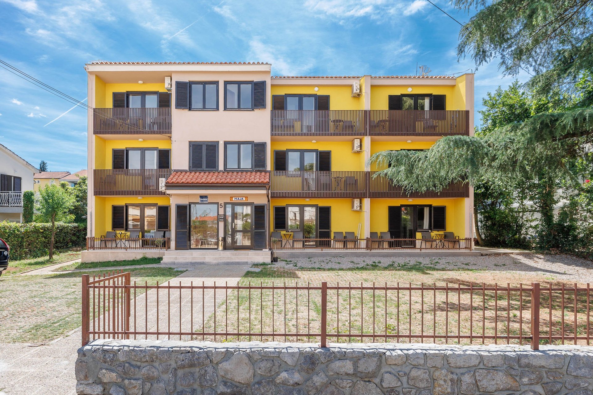 MAJA Apartmani Malinska — Žuta zgrada s drvenim detaljima