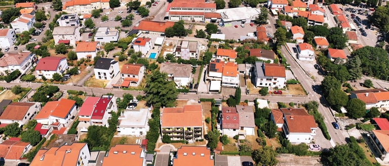 Zračni pogled na mirno stambeno naselje Malinske s terakota krovovima i zelenilom