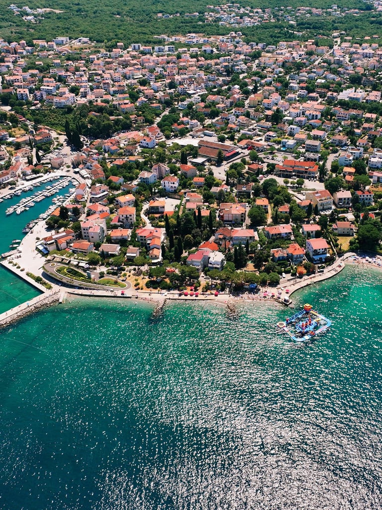 Zračni pogled na Malinsku — crveni krovovi, tirkizno more i marina na otoku Krku