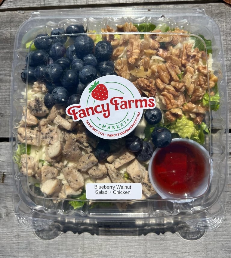 Fancy Farms Blueberry Walnut Salad with Chicken in clear plastic container with fresh greens, blueberries, walnuts, and red dressing