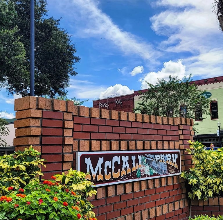 McCall Park brick entrance sign with landscaping and a green building visible in the background