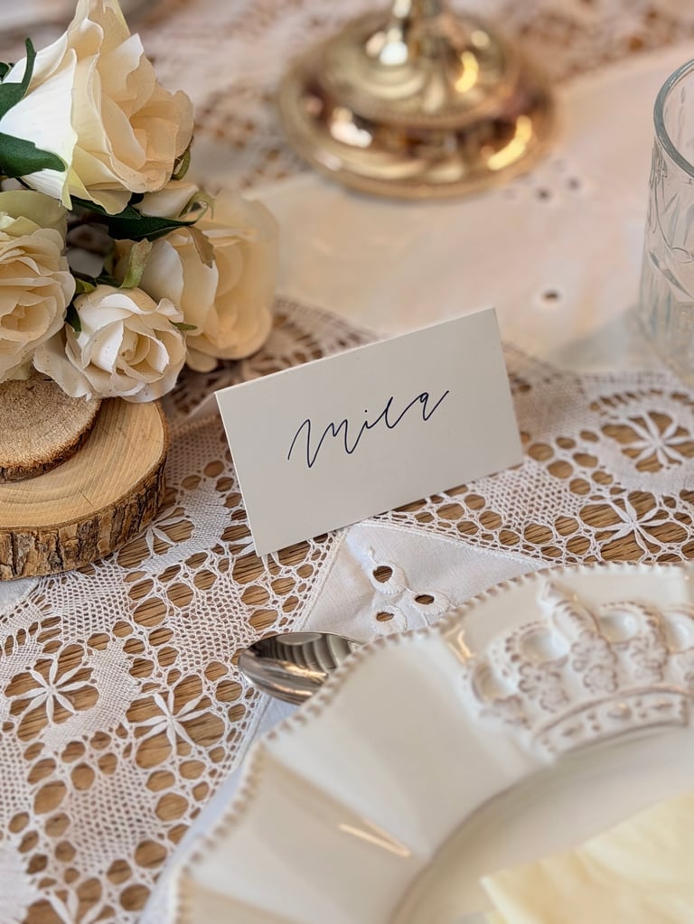 Elegant table setting with cream roses, name card, and lace tablecloth for formal dinner event