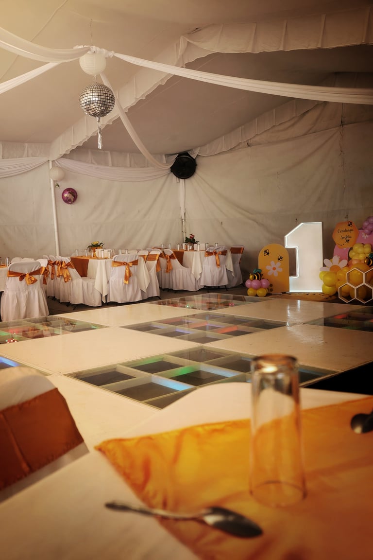 Party venue decorated with sheer white drapes, disco ball, and colorful balloons including a large gold number 1