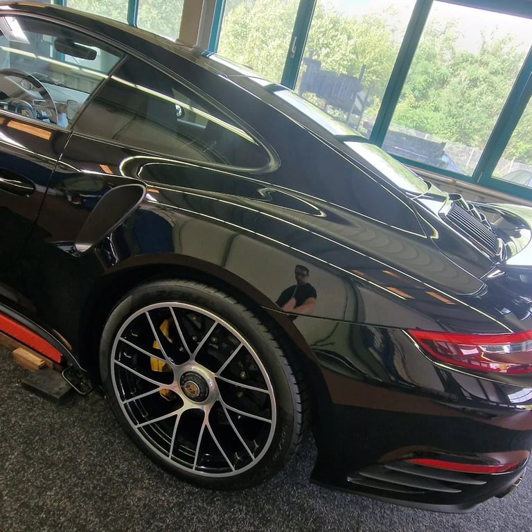 Schwarzer Porsche 911 mit Alufelgen im Showroom