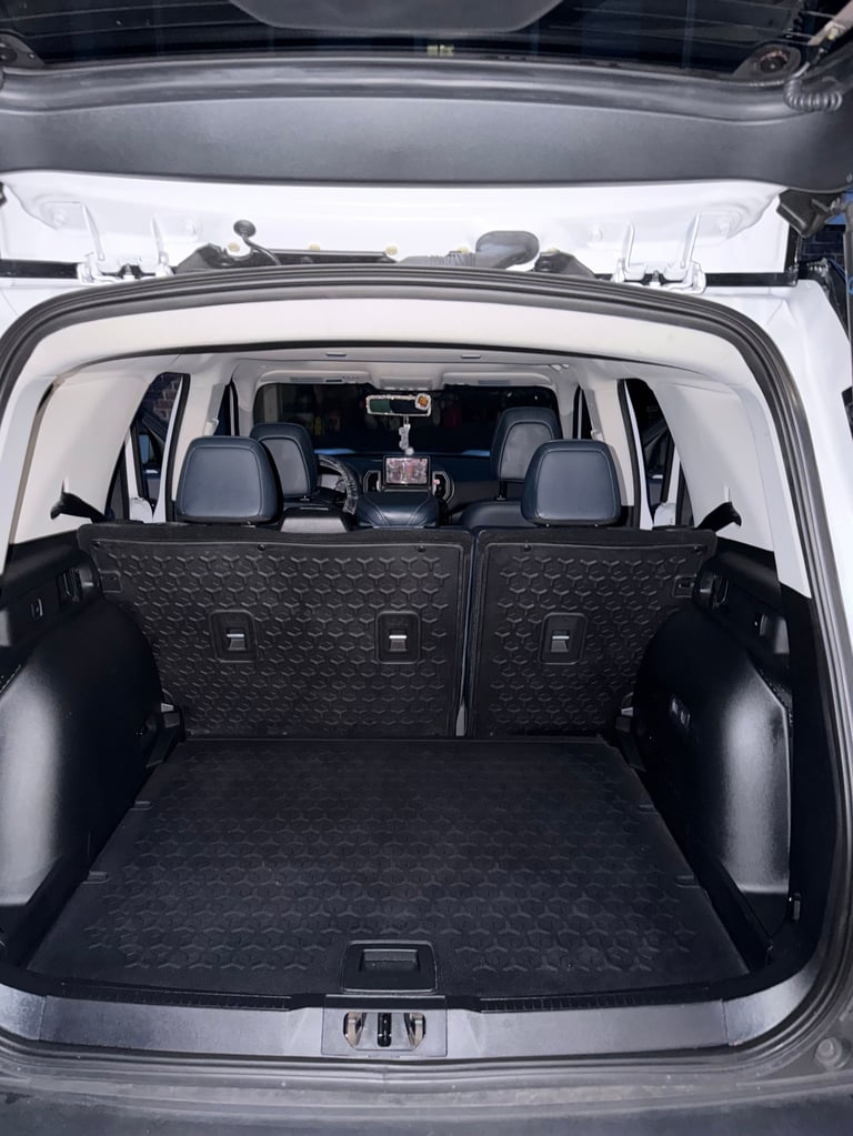 Interior view of a white SUV with open hatchback, showing empty cargo space and rear seats