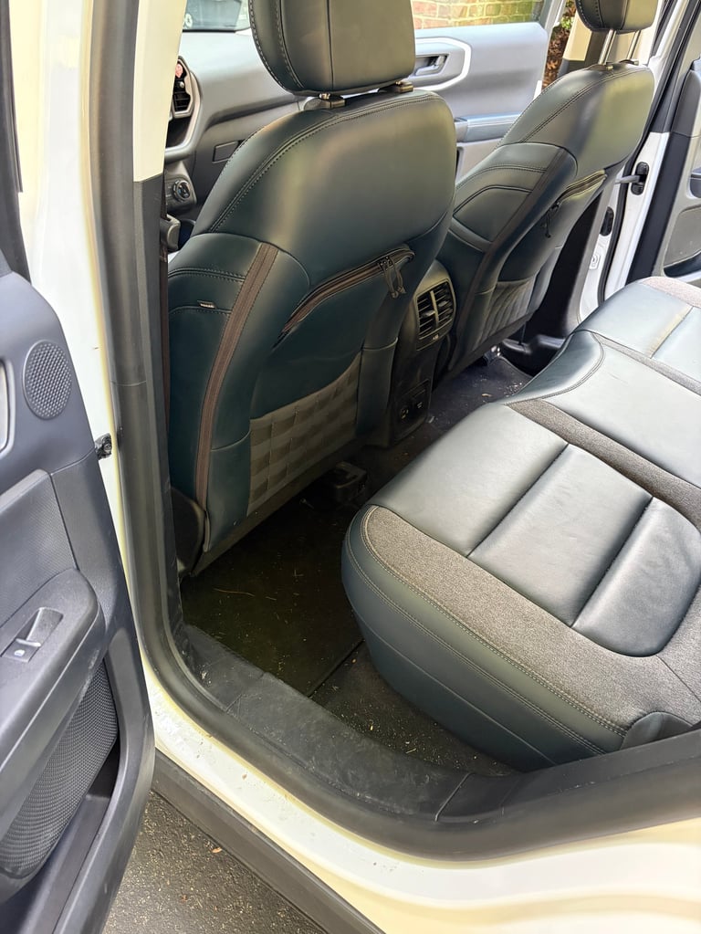 Interior view of a car showing black leather back seats and front passenger seat with open door