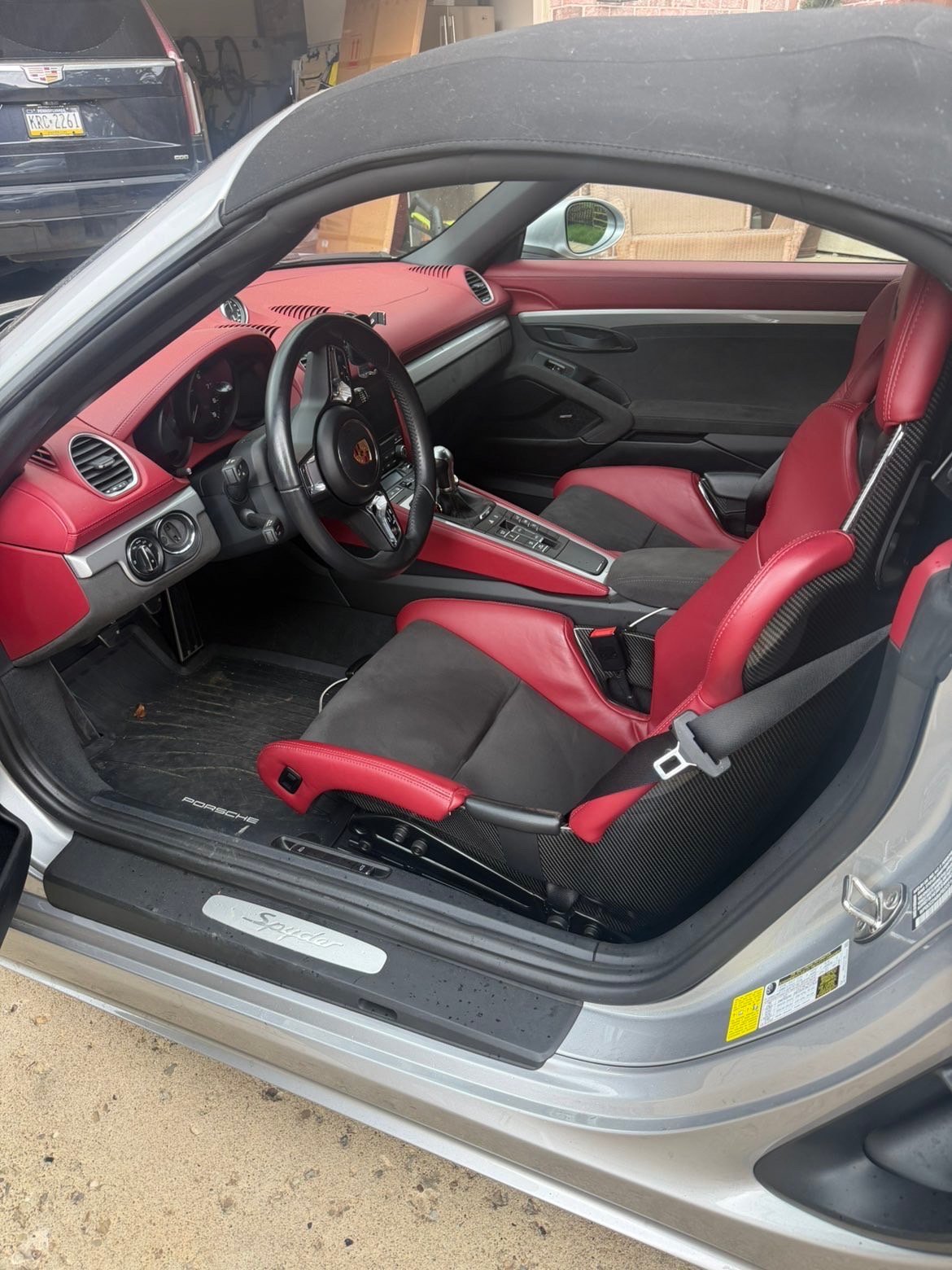 Interior view of a sports car with red and black leather seats, steering wheel, and dashboard through open driver door