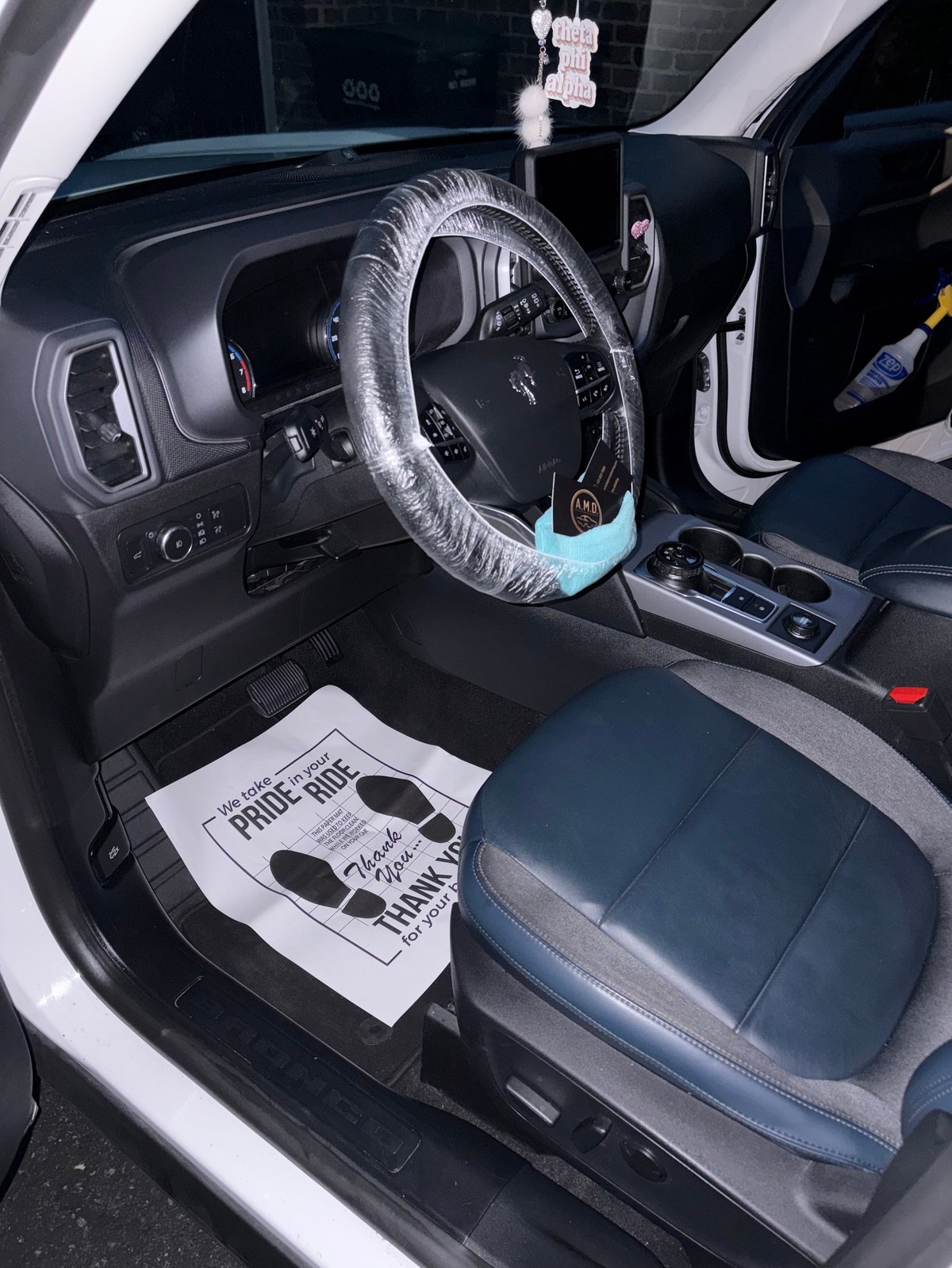 Car interior with protective plastic covering on steering wheel and floor mat