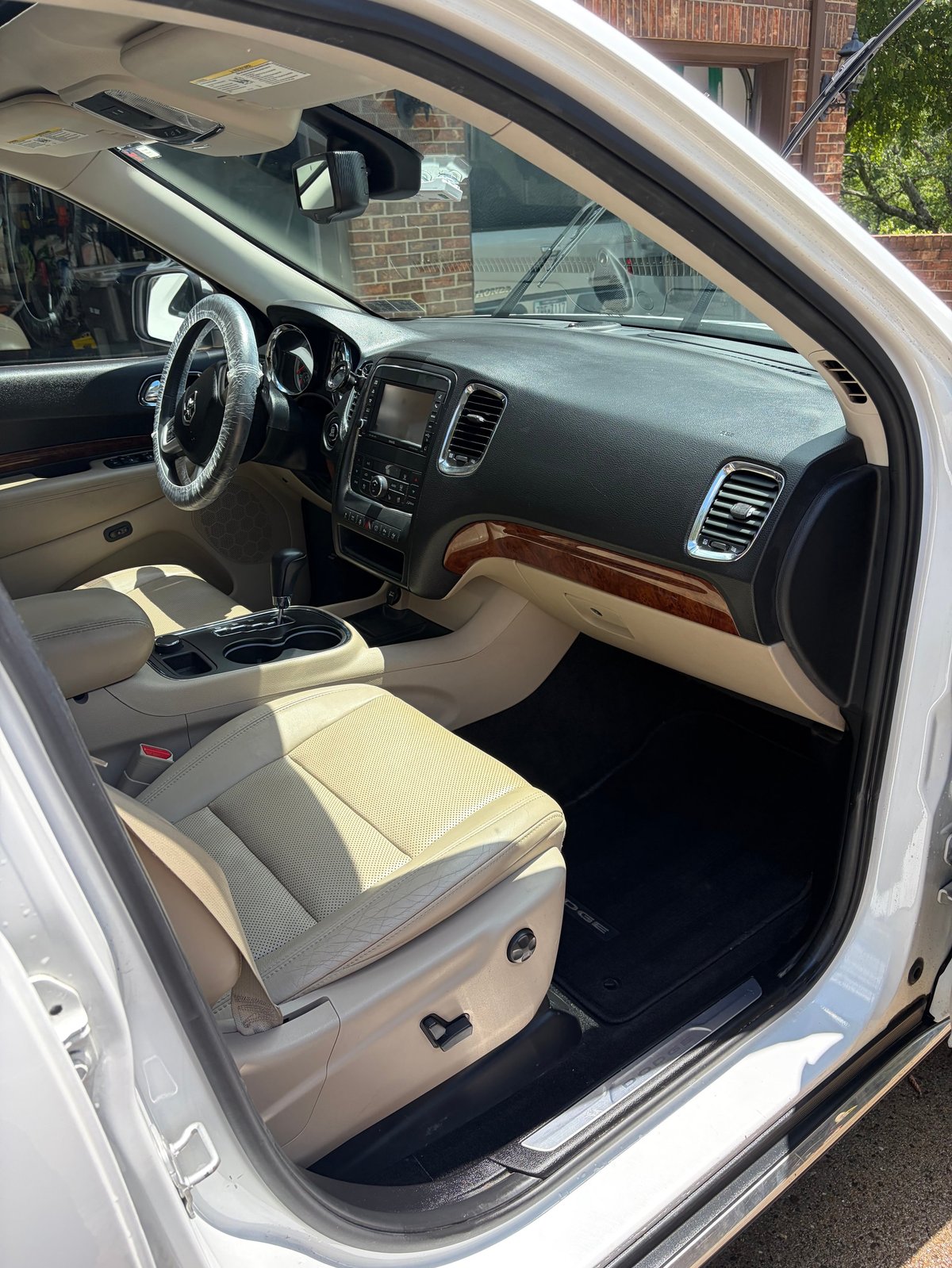 Interior of white luxury SUV with beige leather seats and wood-trimmed dashboard
