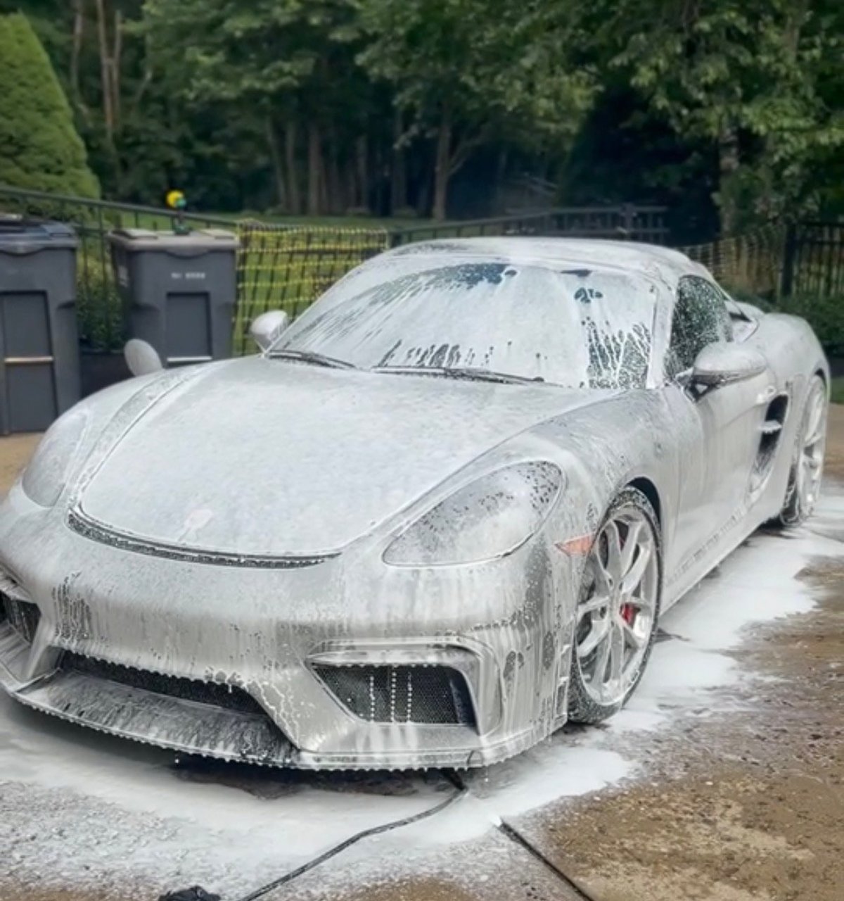 White sports car covered in foam during outdoor hand washing