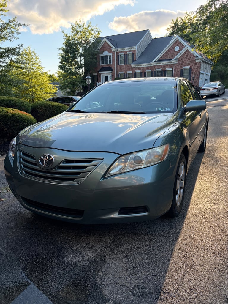 Silver Toyota Camry parked in driveway of brick house on sunny day after detailing