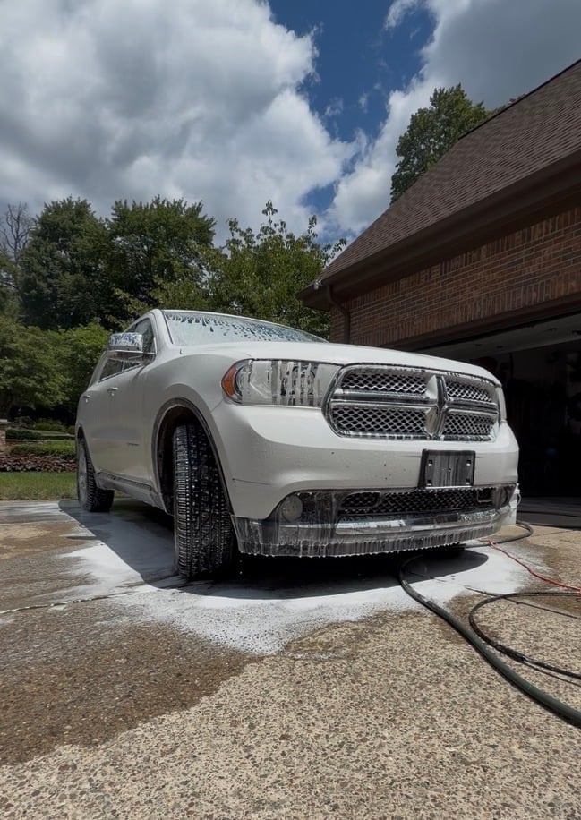 White Dodge Durango SUV parked in driveway outside brick garage being washed