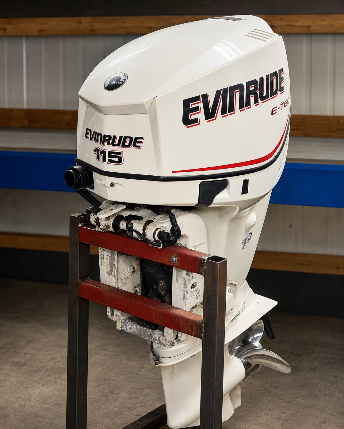 White Evinrude 115 outboard motor mounted on a red metal support stand in a warehouse setting.