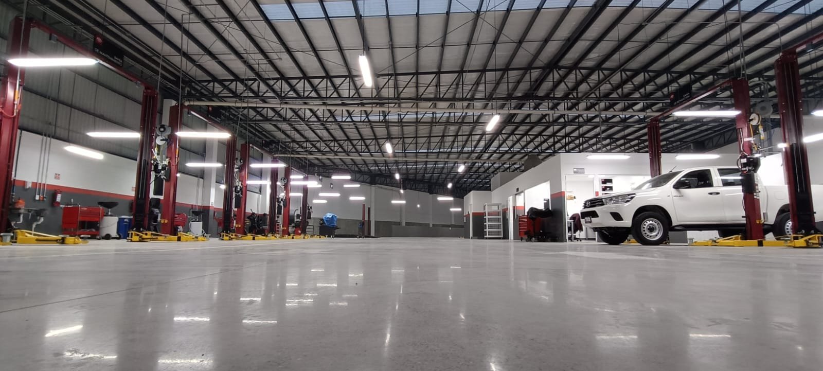 Spacious automotive service garage with white truck at lift station and fluorescent overhead lighting