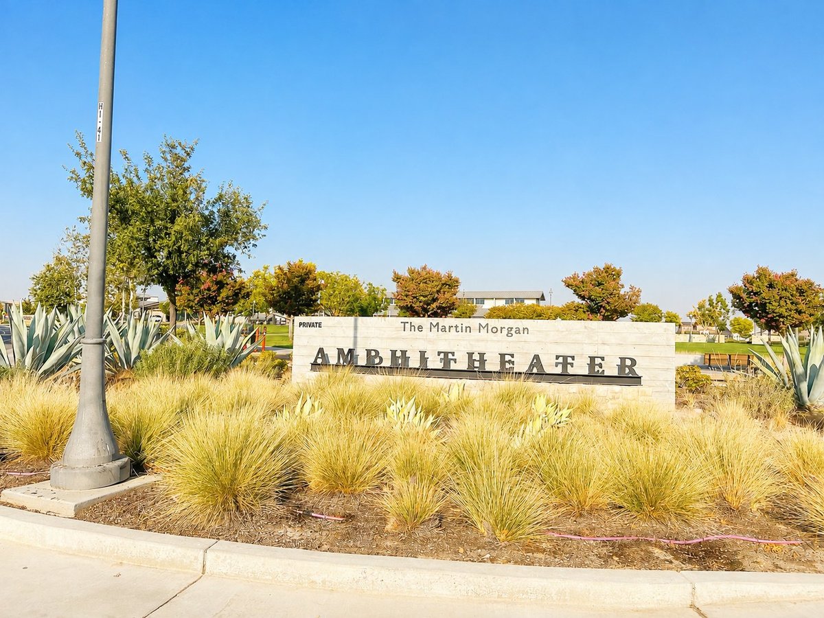 Entrance sign for The Martin Morgan Amphitheater surrounded by ornamental grasses and desert landscaping under clear blue sky