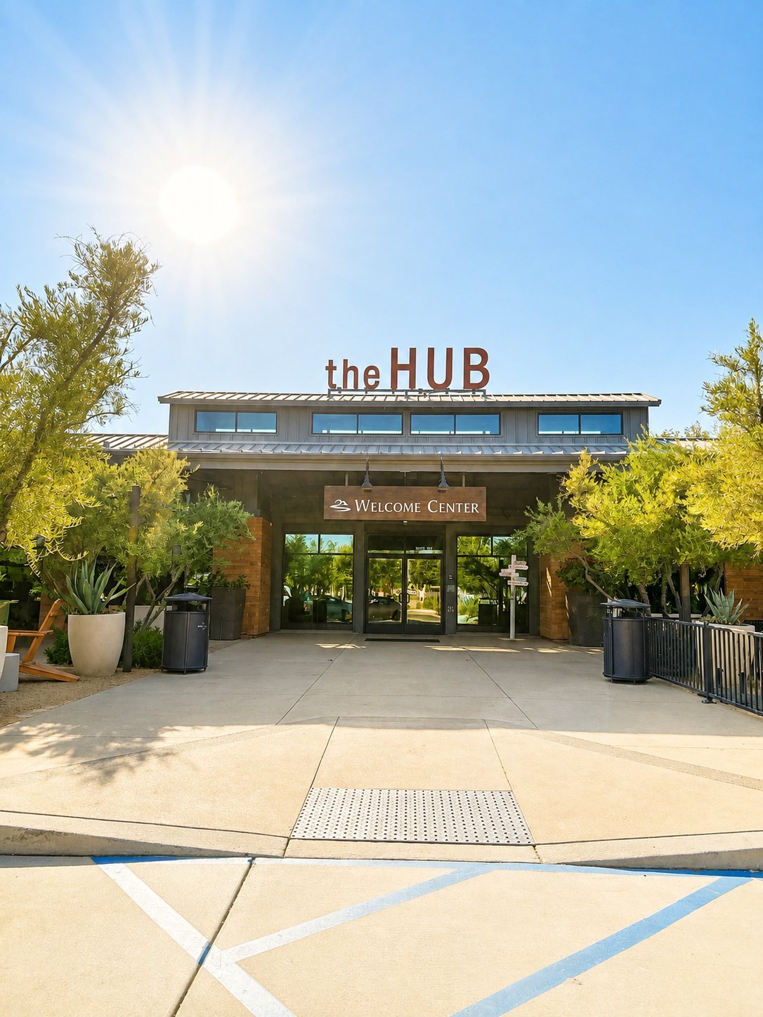 The HUB Welcome Center entrance with modern architecture, large glass doors, and landscaped grounds under clear blue sky