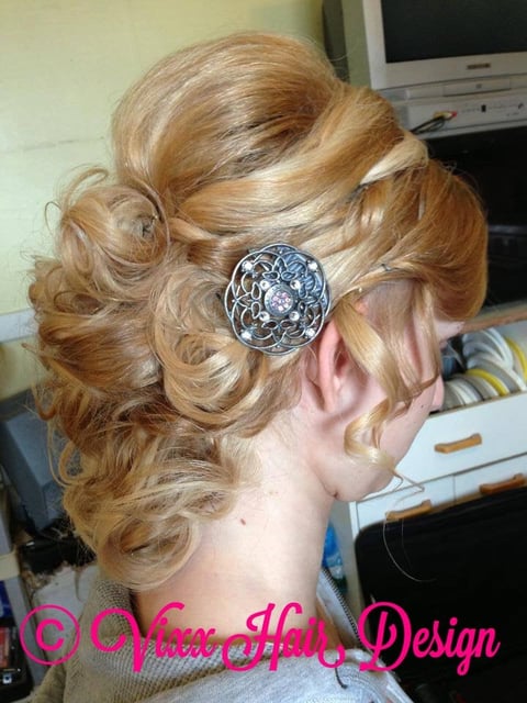 Updo hairstyle with golden blonde curls pinned with a decorative silver circular brooch