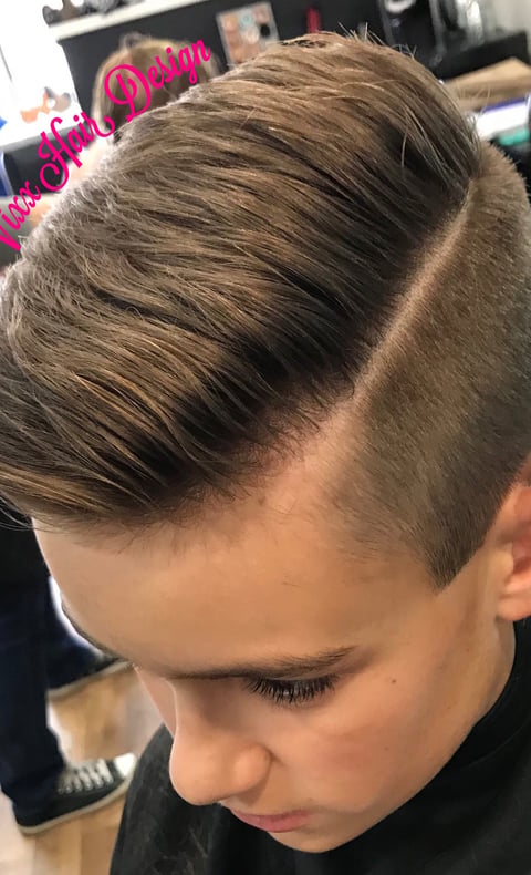 Close-up of a boy with a modern undercut hairstyle, featuring short faded sides and longer styled hair on top with red and green streaks