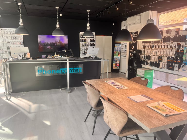 Modern tech retail store interior with wooden table, pendant lights, service counter with blue signage, and product displays on walls