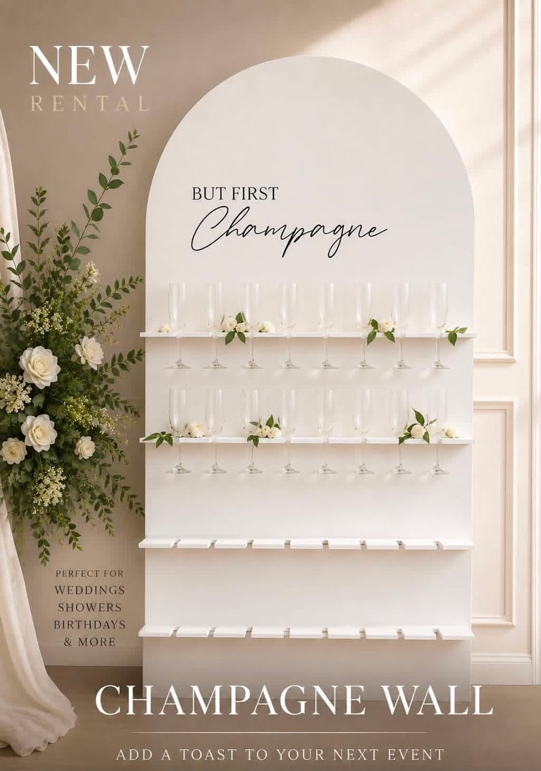 New champagne wall rental display with shelves holding champagne glasses, green foliage, roses, and But First Champagne text