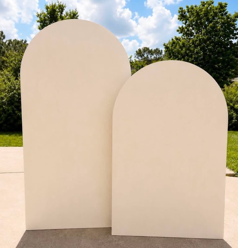 Two large white arched architectural structures on concrete ground with green trees and blue sky in background