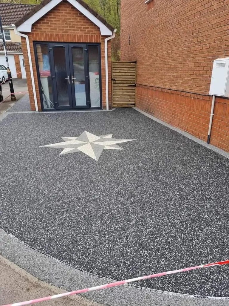 Modern brick driveway with white star design, featuring a contemporary garden studio with dark doors and a white utility box on the brick wall