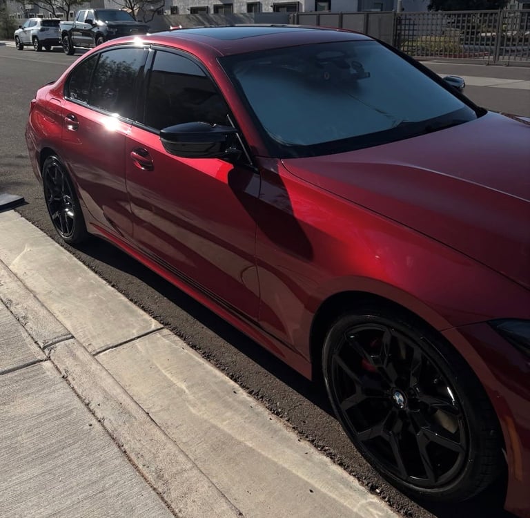 Red sedan with dark tinted windows and black alloy wheels parked on a residential street