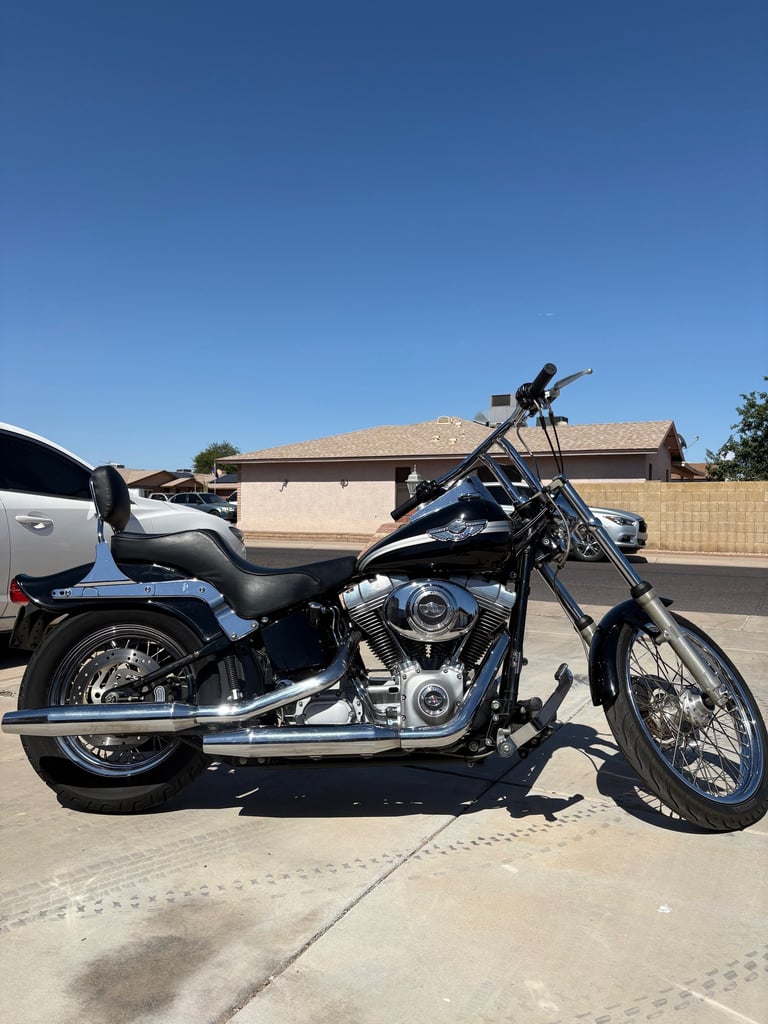 Blue and black motorcycle parked on a driveway with residential buildings in the background under clear blue sky