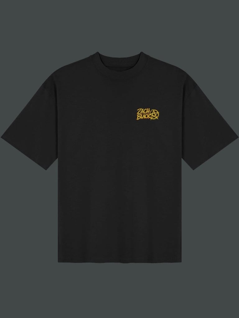 Black t-shirt with small yellow Stüssy logo on chest against gray background