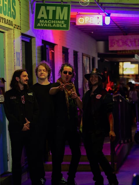Group of four on a neon-lit street at night