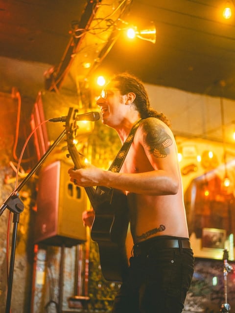 Shirtless musician under warm stage lighting